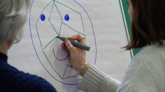 Woman drawing facial recognition technology on a flipchart
