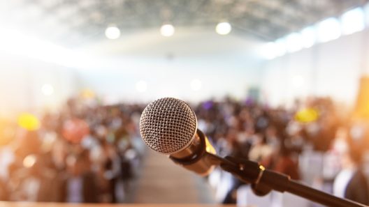 A waiting crowd in front of a microphone and podium
