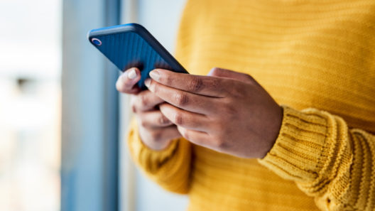 Close up of a woman's hand holding a mobile phone. We can't see the screen.