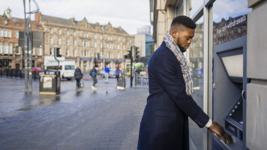 A man in a suit withdrawing money from an ATM in the UK