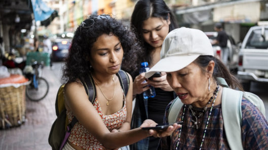 Female tourists holds a phone out for their tour guide to translate during a city tour