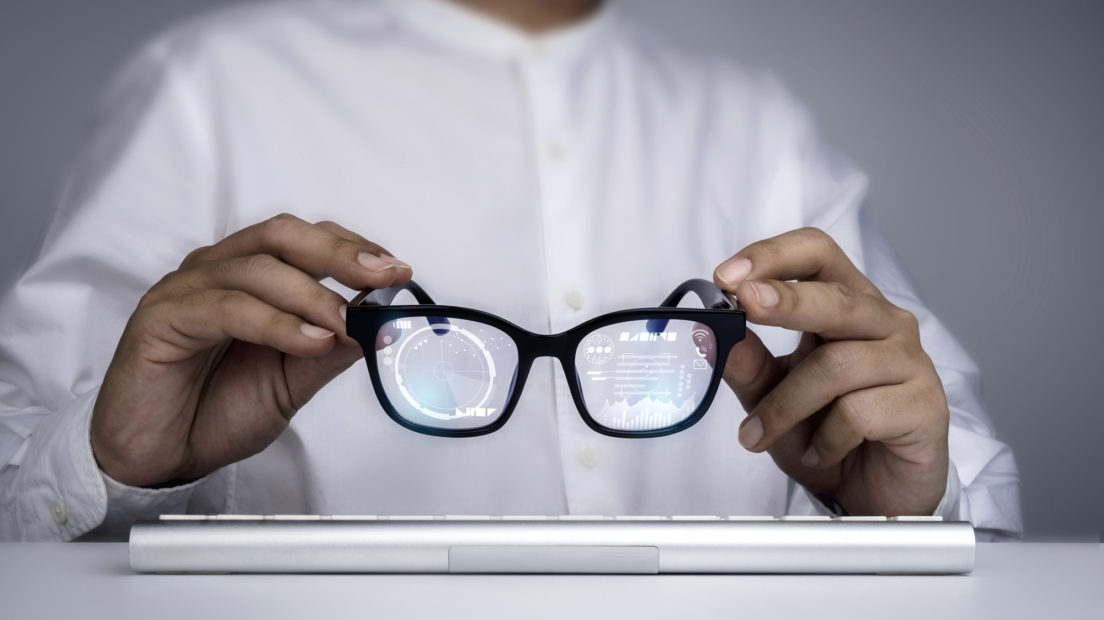 Smart glasses. Businessman in white shirt holding smart glasses with digital information on virtual screen high tech interface. Futuristic technology and augmented reality concept.